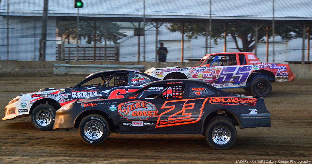 Kyle Falck (67), Brayden Gjere (23) and Troy Hansmeier (55) battle during their American Racer USRA Stock Car heat race. Falck went on to win the night's main event.